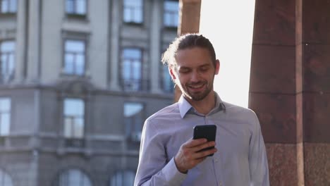 Hombre-de-negocios-utilizando-el-teléfono-móvil-en-la-calle-en-día-soleado