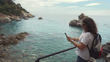 Tourist-Frau-ist-erstaunliche-Landschaft-mit-Meer-per-Smartphone-fotografieren