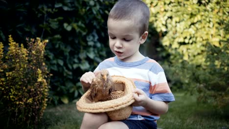 Filmmaterial-Bauernjunge-hält-eine-kleine-Küken-in-den-Händen-im-Freien.