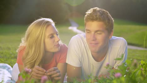 PORTRAIT:-Young-student-couple-calling-home-while-lying-in-the-tranquil-meadow.