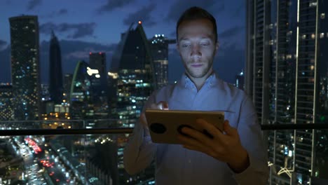 Hombre-joven-usando-la-tableta-para-hablar-y-comunicarse-con-el-fondo-de-la-vista-rascacielos