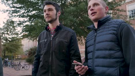 Low-angle-of-two-male-college-students-standing-at-a-university-campus