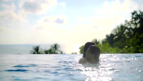 Two-girls-playing-in-the-outdoor-pool-on-a-sunny-day-on-a-tropical-island