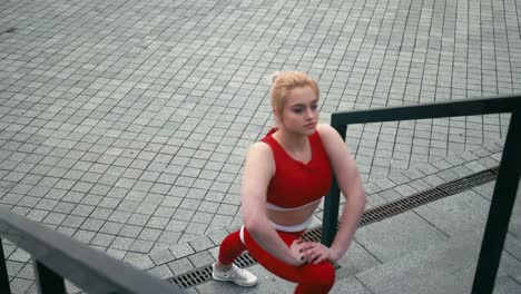 Plus-size-mixed-race-blonde-smiling-woman-wearing-red-sportswear-warm-up-before-run