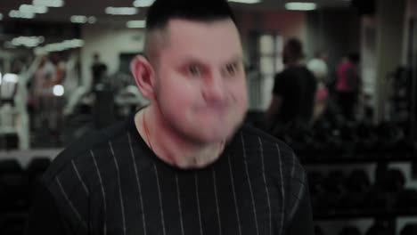 Cheerful-fat-man-performs-a-wrong-exercise-in-the-gym.-For-the-first-time-in-a-fitness-club