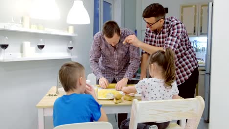 Gay-family-with-two-kids-cook-pizza-together-in-the-kitchen.