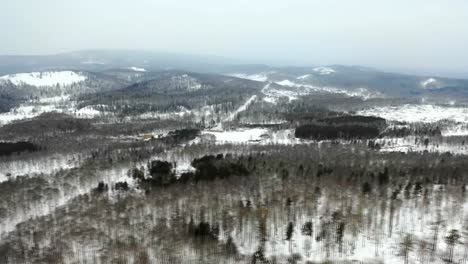 aerial-view-to-snowy-woods-forest-and-hills.-Cloudy-bad-overcast-foggy-weather.-drone-flight.