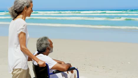 Seitenansicht-der-aktiven-älteren-Afroamerikanerin-mit-behinderten-älteren-Mann-am-Strand-bei-Sonnenschein-4k