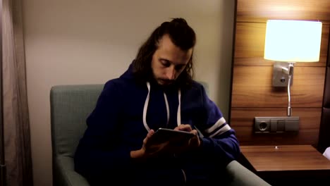 Handsome,-young-man-with-tablet-computer-sitting-on-chair-at-home