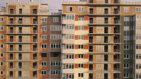 Aerial-view-of-the-facade-of-a-residential-apartment-building-under-construction.-High-rise-building-with-windows-and-balconies.-Construction-industry.-Urbanization