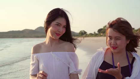 Young-Asian-lesbian-couple-walking-on-beach.-Beautiful-women-friends-happy-relax-walking-on-beach-near-sea-when-sunset-in-evening.-Lifestyle-lesbian-couple-travel-on-beach-concept.