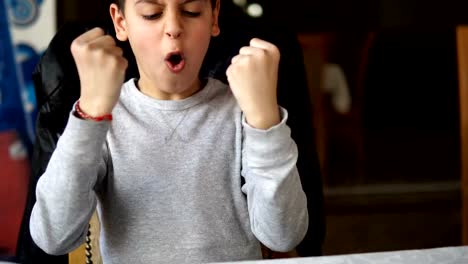 Winning-a-game.-Happy-boy-looking-shocked-with-opened-mouth-and-hands-up-celebrating-game-win-on-smartphone