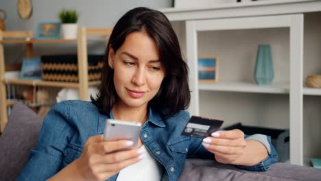 Jovencita-haciendo-pago-en-línea-sosteniendo-tarjeta-de-banco-tocando-la-pantalla-del-teléfono-inteligente