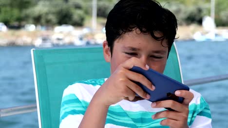 Young-boy-on-boat-using-smartphone