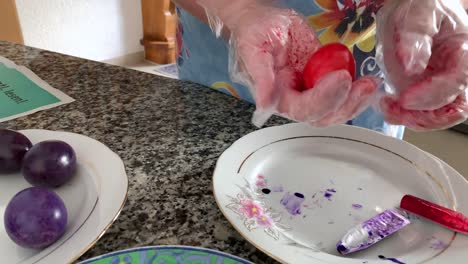 A-woman-in-gloves-paints-eggs