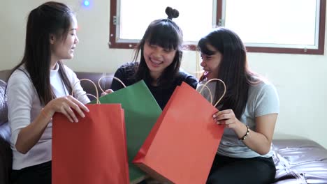 Tres-mujeres-jóvenes-están-disfrutando-de-abrir-bolsas-de-compras