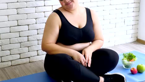 Overweight-young-woman-in-sportswear-choosing-hamburger-rather-than-salad-after-workout