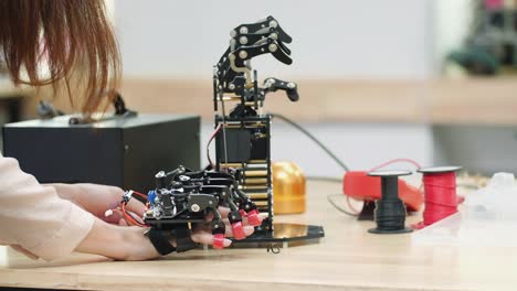 Asian-woman-engineer-assembling-and-testing-robotics-arm-responses-in-laboratory.-Concept-of-robot-technology.