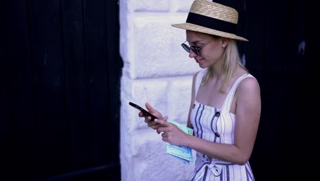 Happy-smiling-female-tourist-enjoying-walking-on-city-urban-setting-typing-text-for-sms-message-with-information-about-location