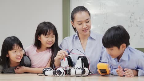 Gruppe-von-Schülern-und-Lehrern-in-der-Roboterklasse.-Berater-in-der-Studentin-über-ihr-Roboterprojekt-erklären.