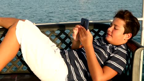 Kind-auf-Yachtdeck-mit-Smartphone