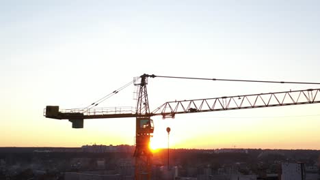 A-construction-crane-swaying-slightly-in-the-wind-against-the-morning-sky.-Close-up,-aerial-video