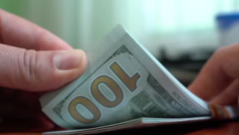 Fingers-sorting-through-a-stack-of-banknotes.-A-stack-of-$-100-bills.-Close-up.-Counterfeit-money.