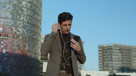 Businessman-walking-with-earphones-on-street.-Employee-using-earbuds-outside