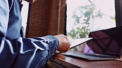 A-young-businessman-wearing-a-surgical-mask-is-doing-a-video-conference-with-customers-via-a-tablet-that-is-connected-to-the-Internet