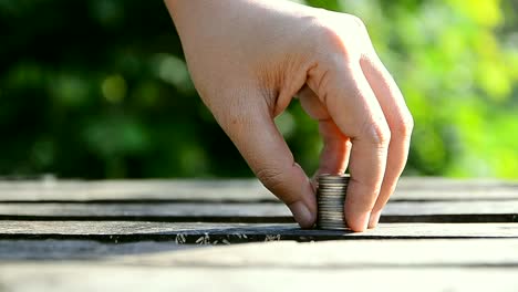 Hand-of-woman-stacking-coins-over-nature-green-leaf-background