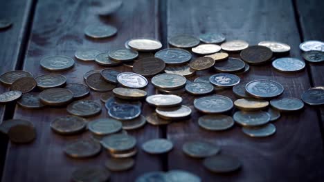 Pile-of-coins-falling-on-the-wooden-table