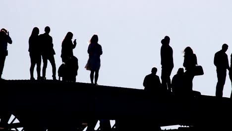 Silhouetten-von-jungen-Menschen-flanieren-und-die-Bilder-von-einander-in-einer-prekären-Situation-auf-der-Oberseite-der-Brücke