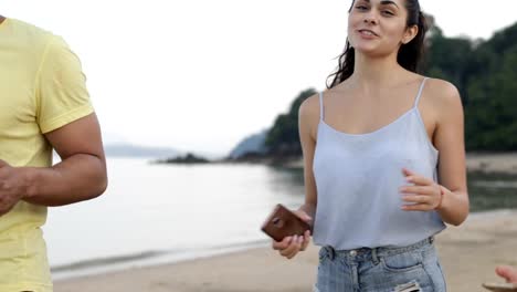 People-Talking-Walk-On-Beach-Hold-Cell-Smart-Phone,-Young-Tourists-Group-Communication