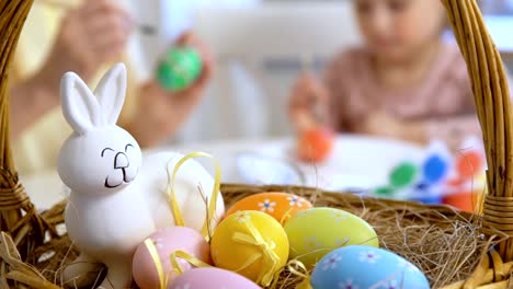 Frohe-Ostern!-Mutter-und-ihre-kleine-Tochter-tragen-lustige-Hasenohren-Ostereier-färben