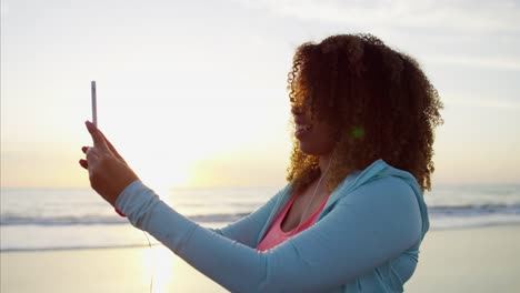 African-American-female-taking-video-walking-on-beach