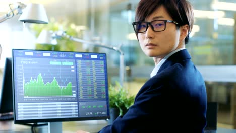 In-the-Stock-Market-Firm-Office-Broker-Works-with-Financial-Markets-Data,-in-Cryptocurrency-Branch.-Dramatically-Turns-His-Head-and-Looks-into-the-Camera.-Stylish-Concrete-and-Glass-Office-Shared-with-Beuatiful-Coworker.