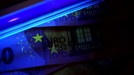 Counterfeit-money-detecting.-Cheking-euro-banknotes-with-uv-light.