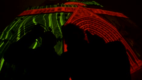 Two-friends-sitting-and-drinking-beer-under-cathedral-illuminated-by-lightshow