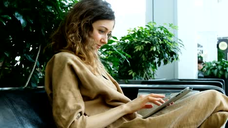 Businesswoman-sitting-on-the-couch-business-center-and-using-a-tablet