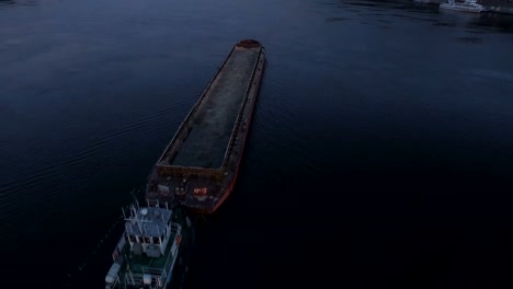 Barge-sails-along-the-river-near-the-city-port-on-sunset-aerial-footage