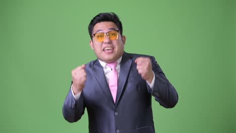 Young-handsome-overweight-Asian-businessman-against-green-background