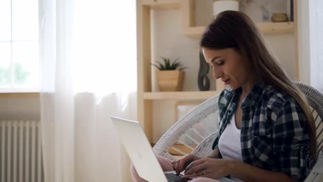 Hermosa-mujer-participa-en-el-blog,-sentado-con-el-ordenador-portátil-en-casa-interior