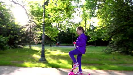 Little-child-learning-to-ride-a-scooter-in-a-city-park