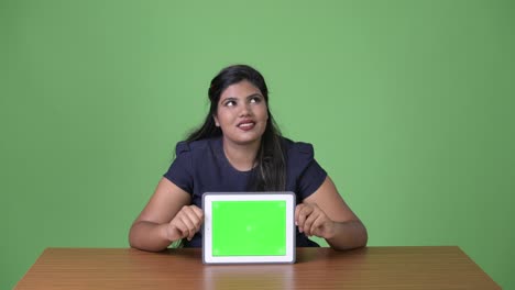 Young-overweight-beautiful-Indian-businesswoman-against-green-background