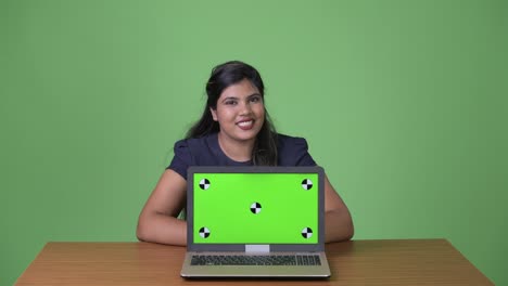 Young-overweight-beautiful-Indian-businesswoman-against-green-background