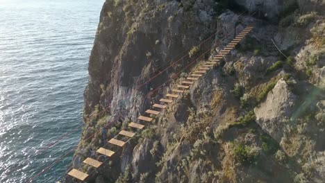 Luftaufnahme-der-Hängebrücke-zwischen-den-Felsen-über-dem-Meer-und-Gefahr-Wellen-und-Steinen