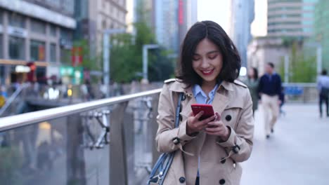 slow-motion-of-pretty-happy-young-asian-woman-walking-in-the-city-street-while-using-smart-phone-at-afternoon