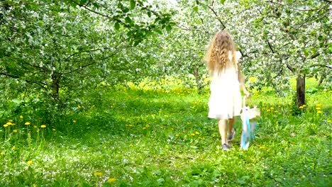 Entzückende-kleine-Mädchen-in-blühender-Apfelgarten-an-schönen-Frühlingstag