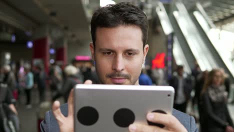 Caucasian-employee-working-online-and-mobile-at-train-station-with-digital-tablet