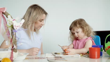 Madre-y-su-pequeña-hija-pintando-huevos-de-Pascua